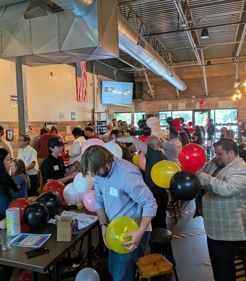 Teams blowing up balloons for the balloon tower challenge