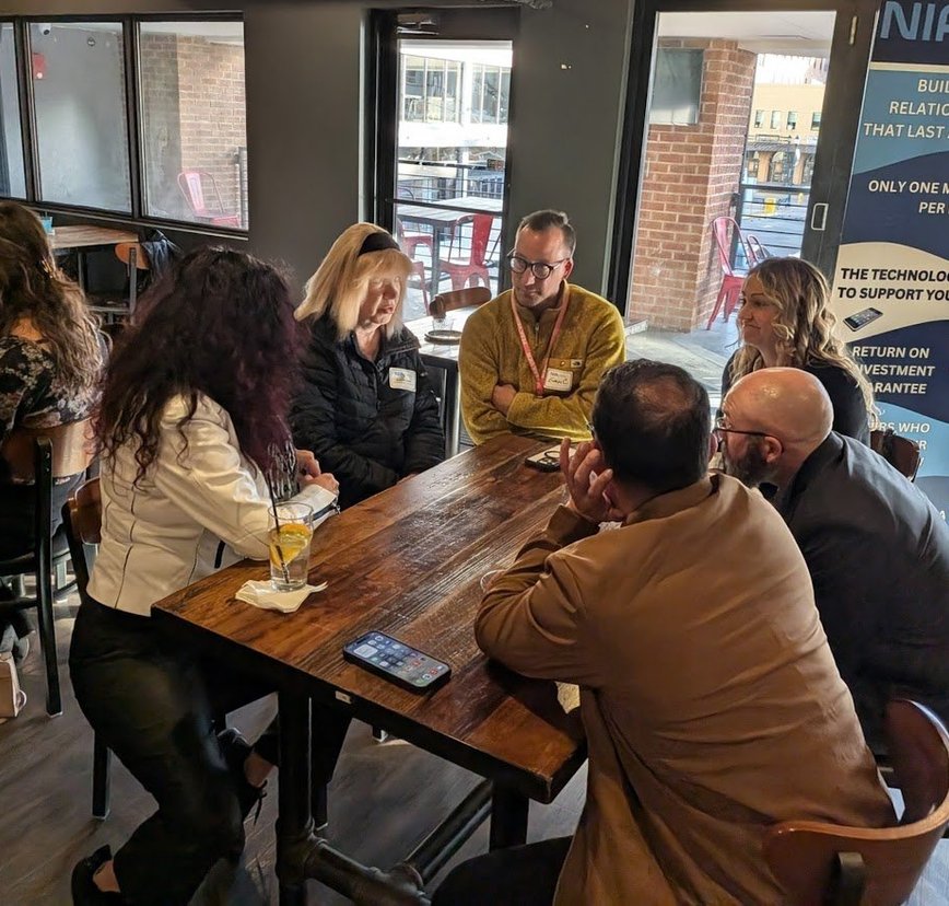 Members at an NIA Colorado Springs meeting, with the NIA banner reading only one meeting per month