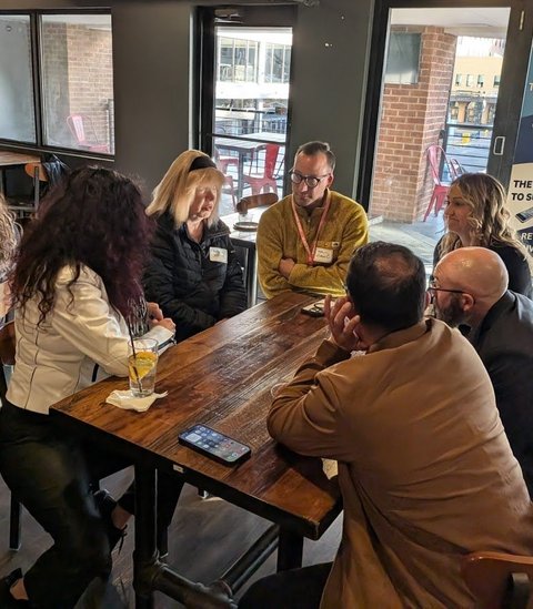 Members talking around a table with the NIA banner behind them