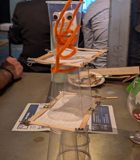 A googly-eyed pipe cleaner creature on top of a cup tower