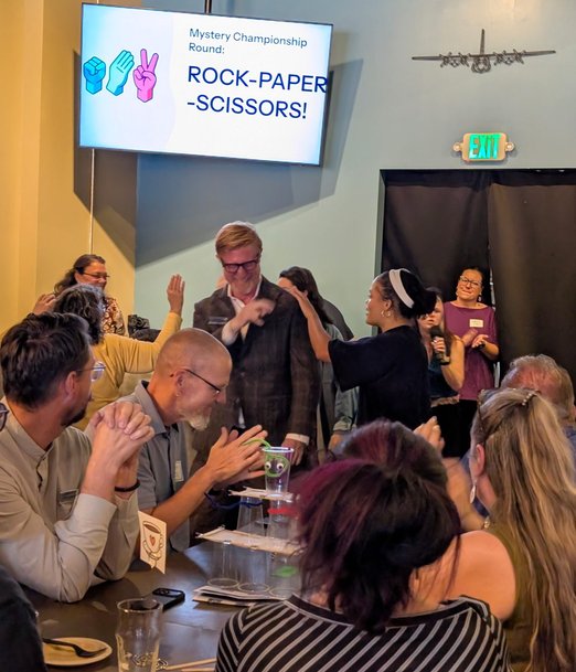 Guests mid-throw during the Rock Paper Scissors championship round at Next Level Networking