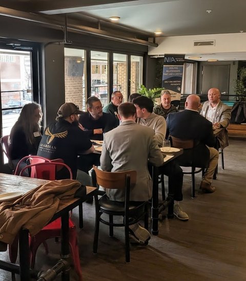 Members spread across several tables in a wide meeting room