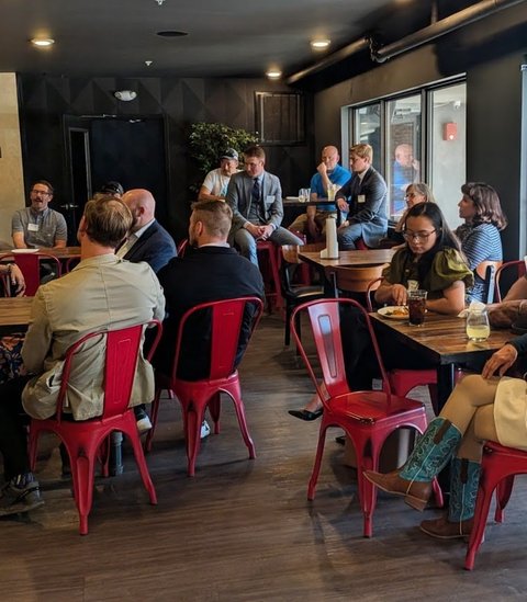 A full room of members on red chairs at a Colorado Springs meeting