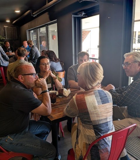 Members in conversation at a table by the windows
