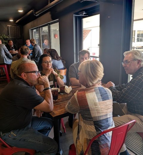 Members deep in conversation around a table at a monthly meeting