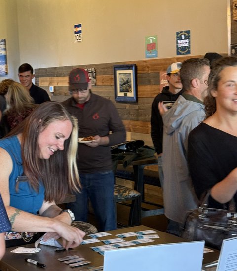 A host laughing at the welcome table as guests arrive