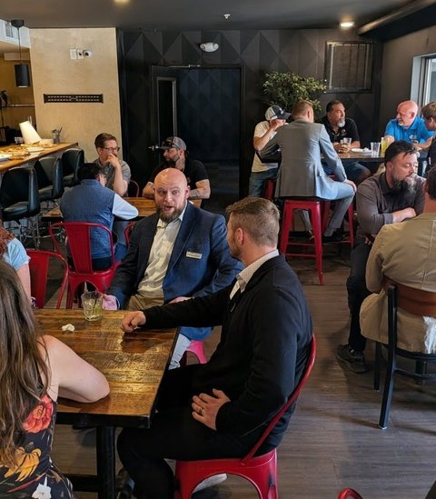 Members at tables along the bar during a meeting