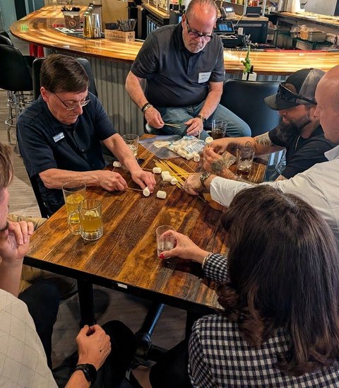 Members building with spaghetti and marshmallows at a meeting
