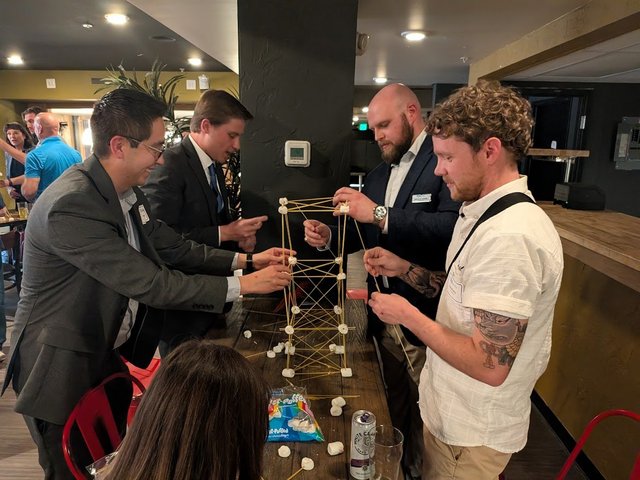 Members building a spaghetti and marshmallow tower at an NIA meeting