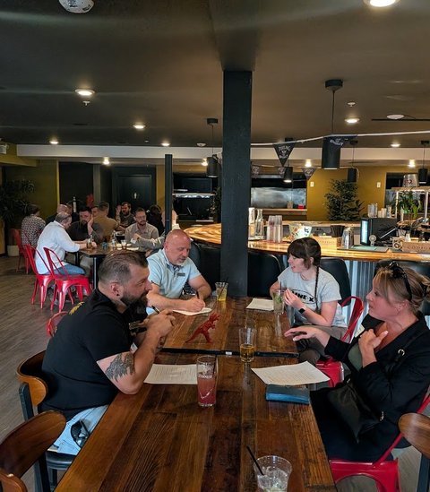 Members around a long table at a Colorado Springs brewery meeting