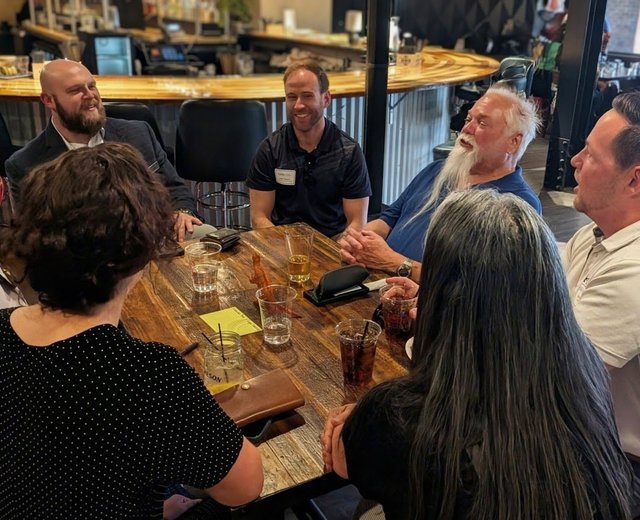 A table of members laughing together at an NIA Colorado Springs meeting