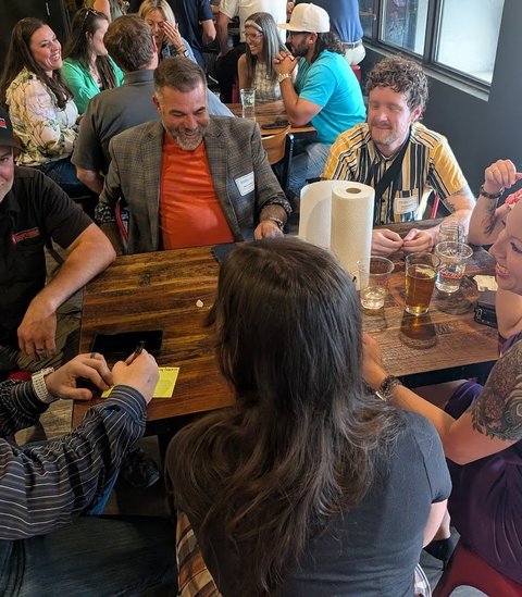Members laughing around a table at a monthly meeting