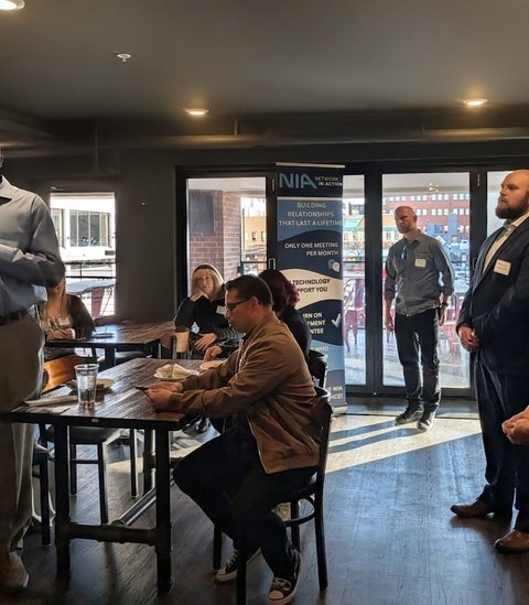 Members standing and talking as a meeting begins