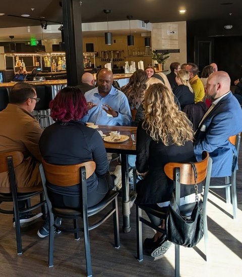 Members at tables in afternoon light during a meeting