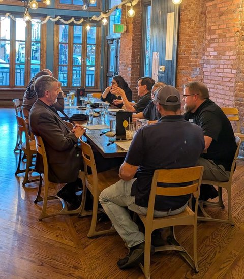 Members at a long table in a brick-walled Colorado Springs venue